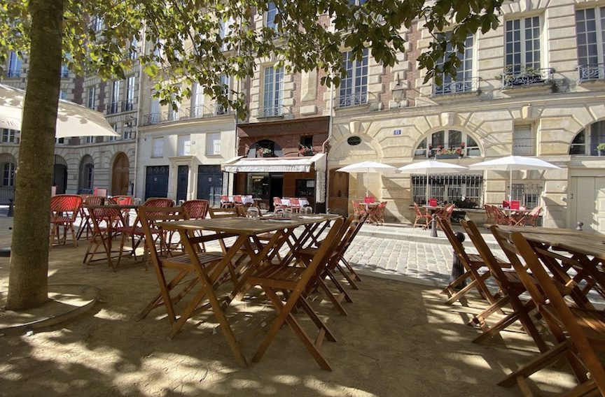 Wooden chairs line the sidewalk.