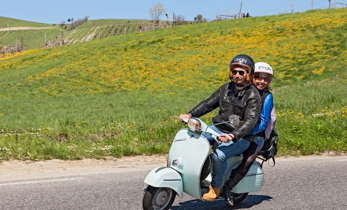 couple ride a vespa through rolling hills on one of our best Florence tours.
