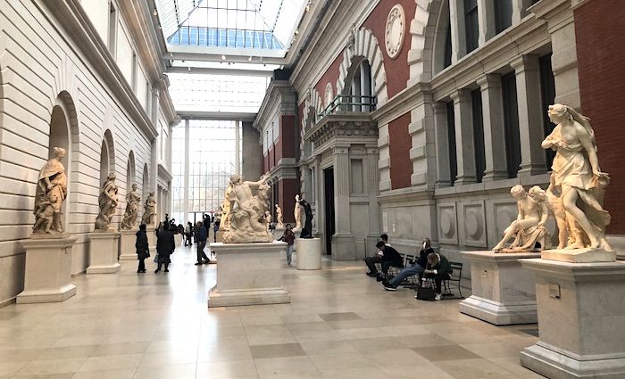 Interior of the Met Museum in NYC with sculptures and visitors