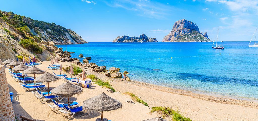 Lounge chairs on beach on the coast of Ibiza.