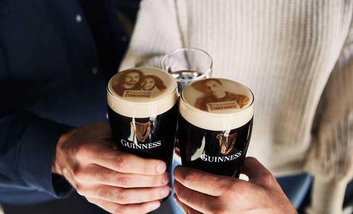 people holding two glasses of guinness