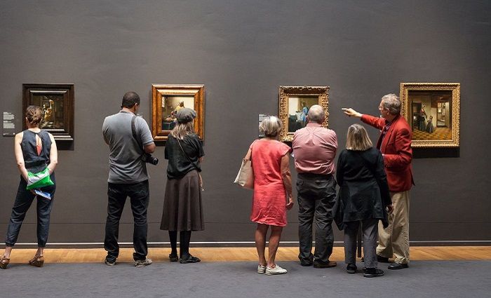 visitors on a Rijksmuseum tour standing in front of paintings