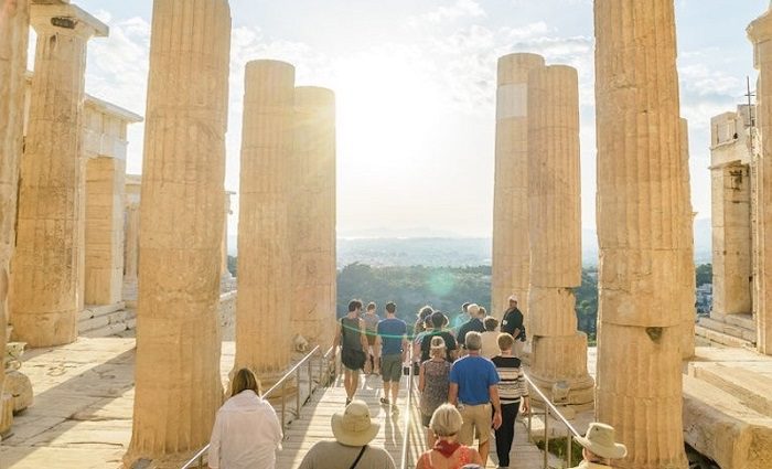 tourists walking through the ruins of a temple on a guided tour of the Acropolis in Athens, Greece 