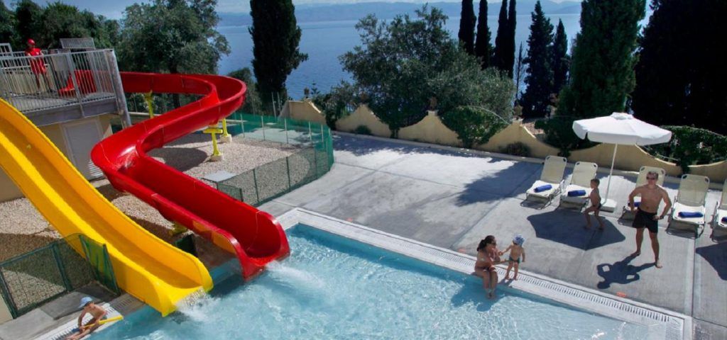 Adults and kids playing in a pool with slides.