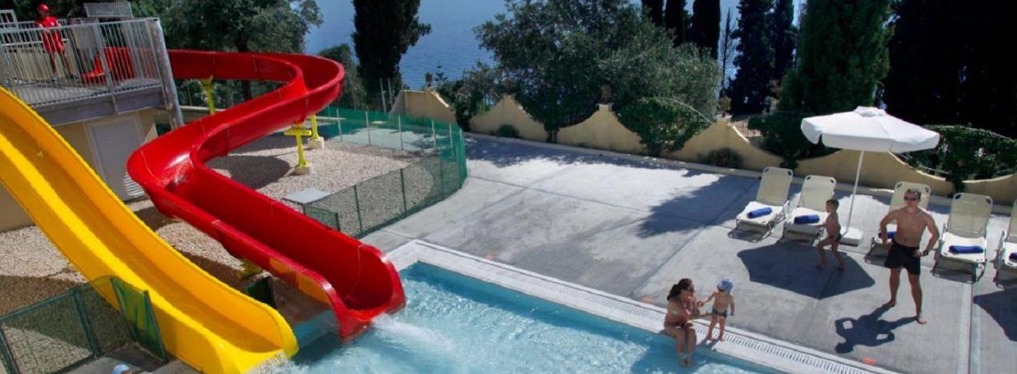Adults and kids playing in a pool with slides.