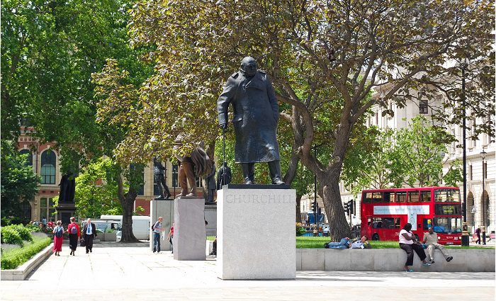 People walking in Parliament Square London with Churchill statue in foreground