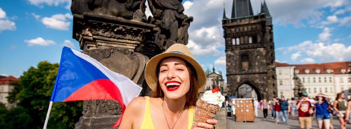 Woman eating ice cream and holding up a Czech flag on the Prague bridge.