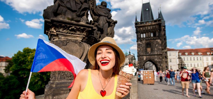 Woman eating ice cream and holding up a Czech flag on the Prague bridge.