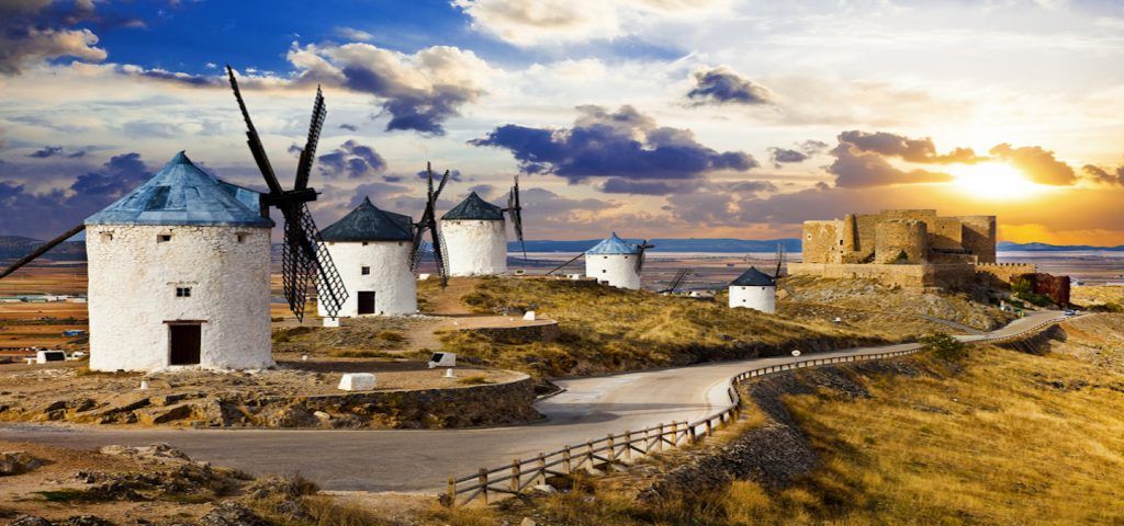 Line of Windmills with castle in the background during the sunset.