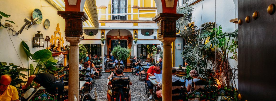 Indoor courtyard with people eating dinner.