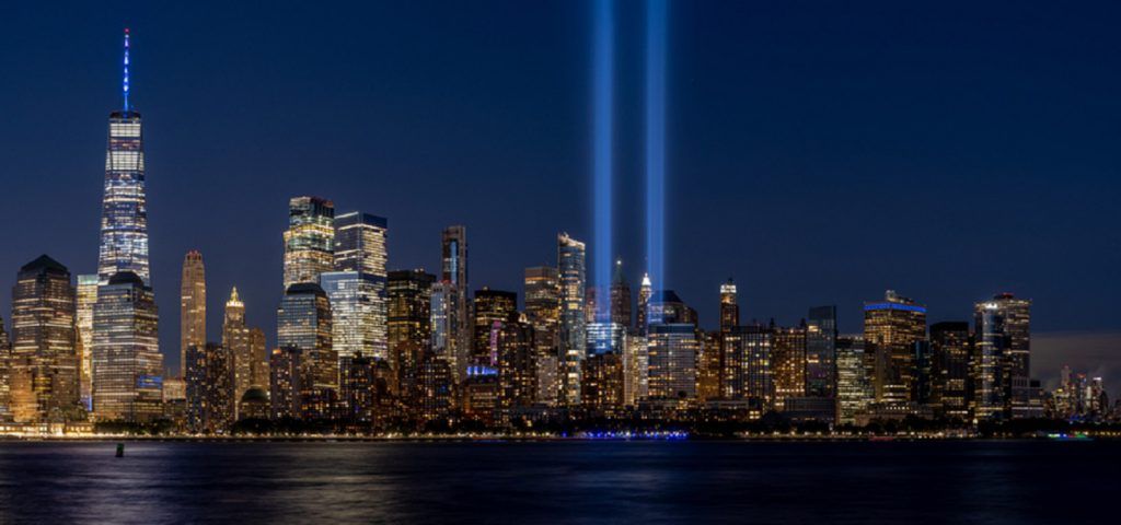 New York skyline with lights coming up from the 9/11 memorial at night.