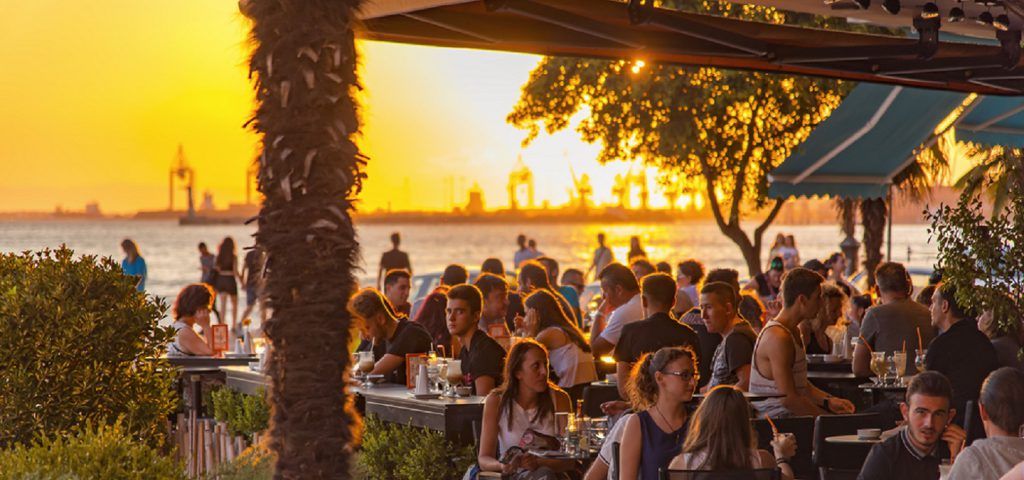 People eating and drinking at a restaurant during sunset.