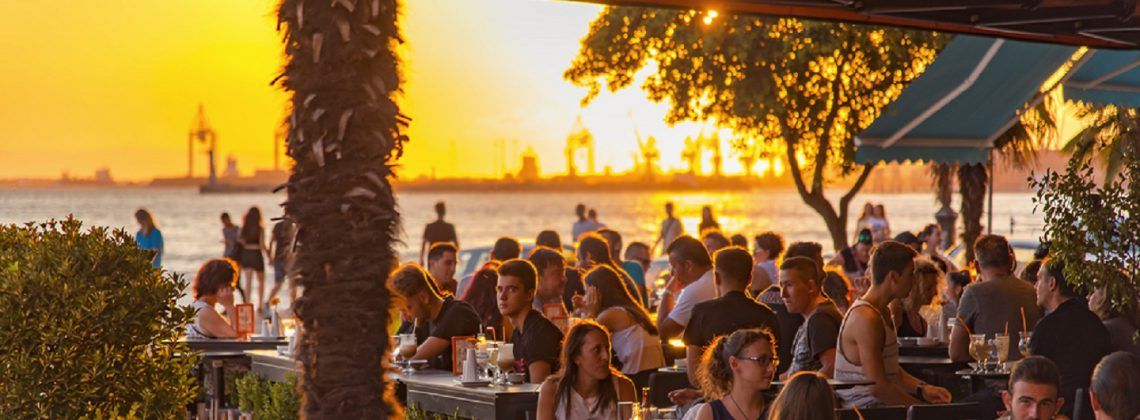 People eating and drinking at a restaurant during sunset.