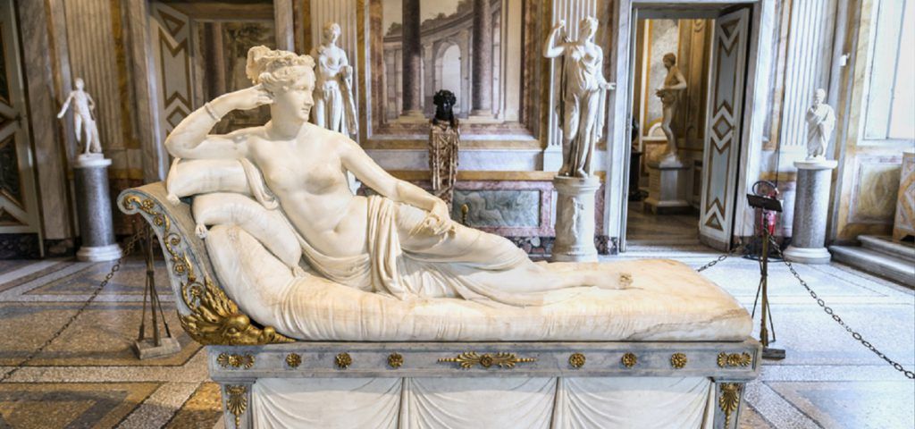 Marble statue of woman resting on a bed.