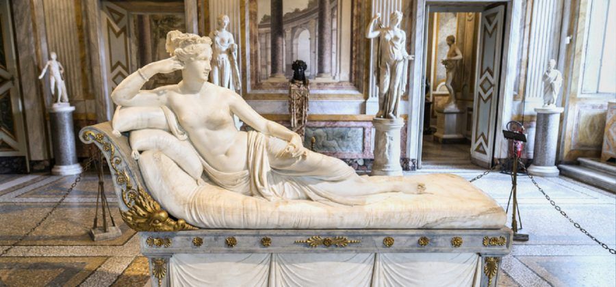 Marble statue of woman resting on a bed.