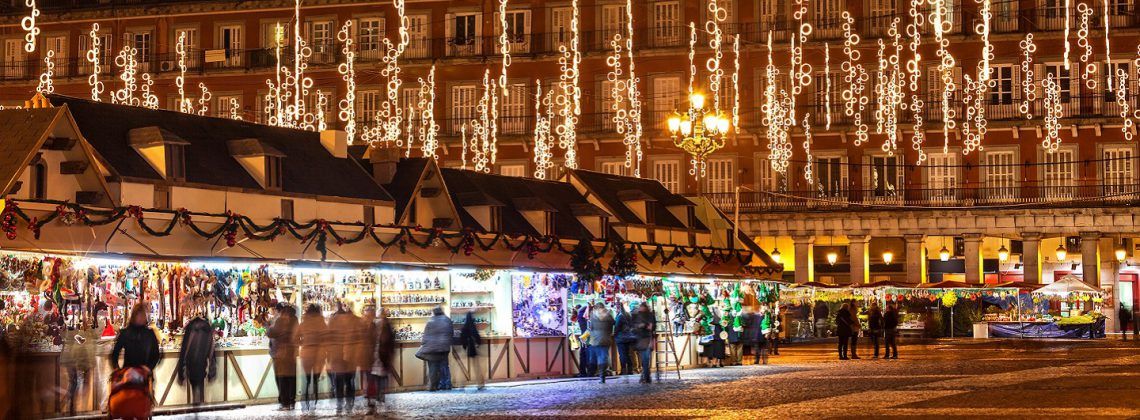 People walking the streets of Madrid with Christmas lights above.