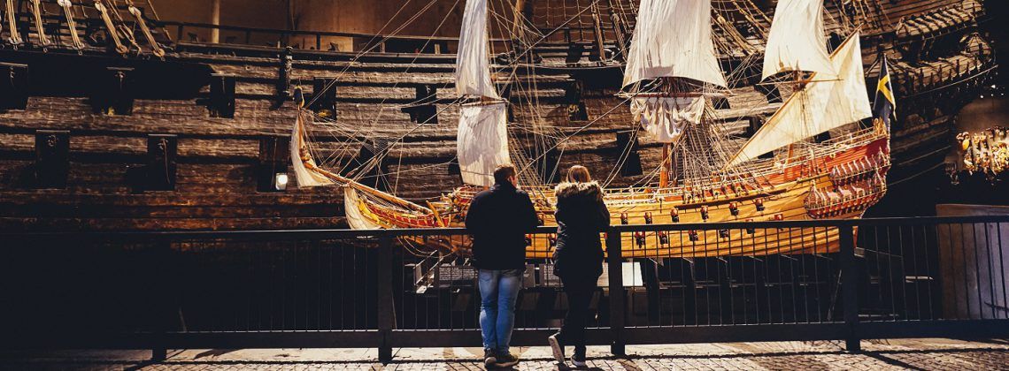 Two people looking at old sailboat at a museum in Stockholm.