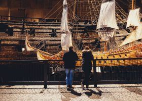Two people looking at old sailboat at a museum in Stockholm.