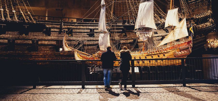 Two people looking at old sailboat at a museum in Stockholm.
