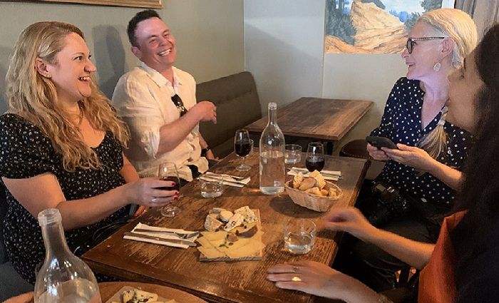 People laughing and drinking wine at a dinner table.