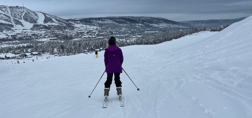 Person wearing purple jacket skiing down mountain