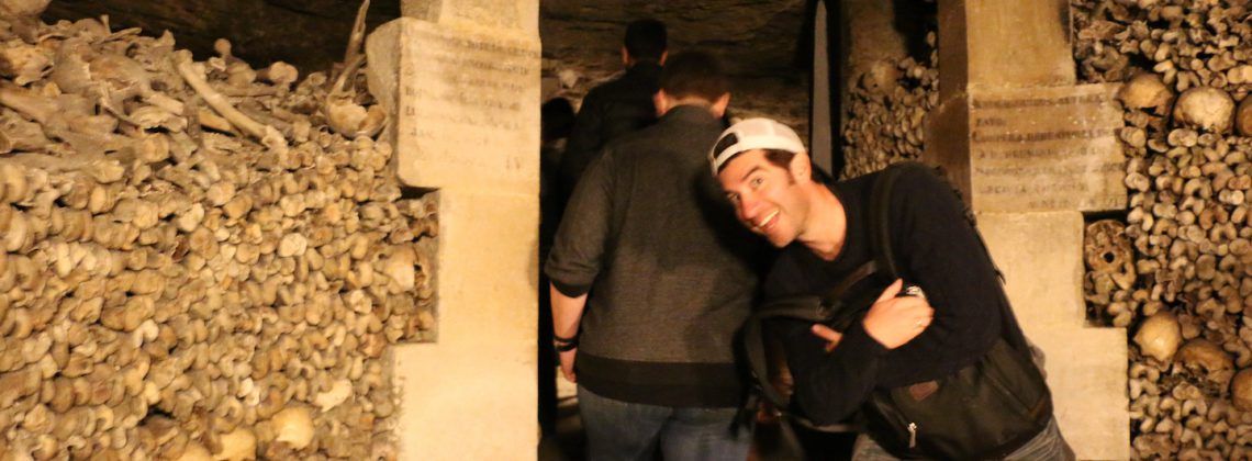 Man posing in the Paris catacombs surrounded by bones.