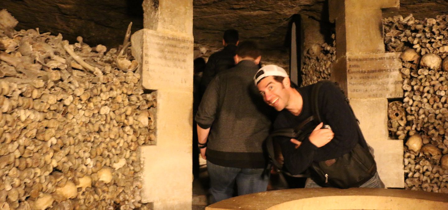 Man posing in the Paris catacombs surrounded by bones.