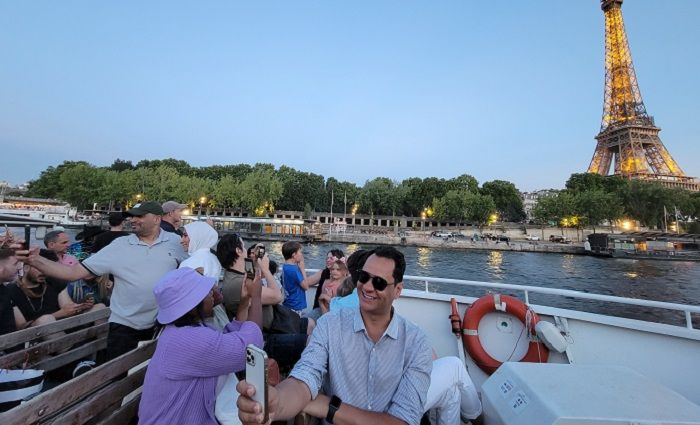People on a guided tour enjoying the views of the Eiffel Tower from their boat on a Seine River cruise at night.
