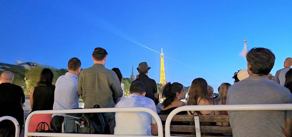 People on river boat with lit up Eiffel Tower in the background.