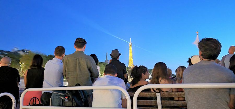 People on river boat with lit up Eiffel Tower in the background.