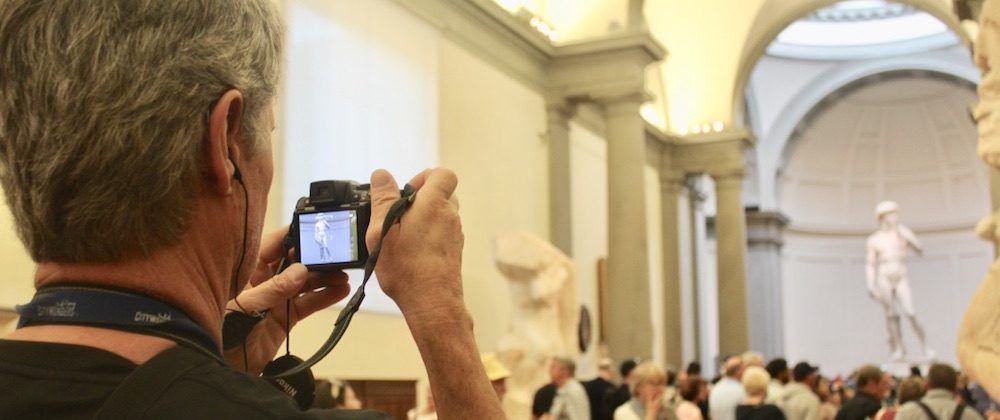 Man taking photo of the Statue of David in Florence.