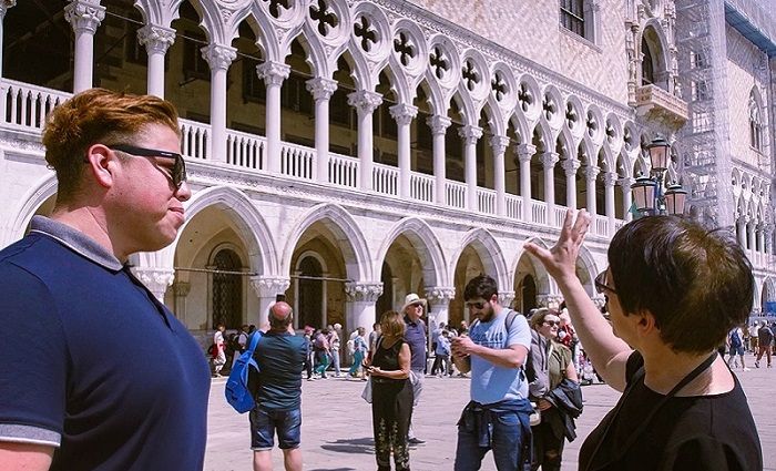 Tour guide with visitor in front of the Doge's Palace in Venice.