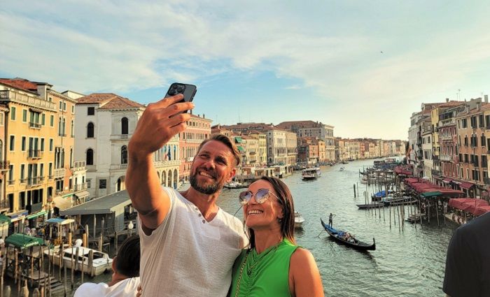 happy couple on a Venice guided tour taking a selfie with the Venice canal in the background