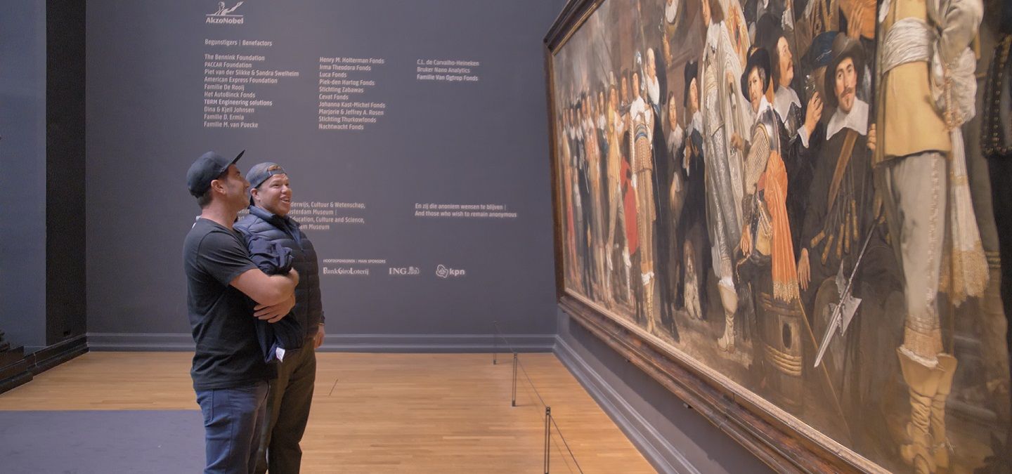 Two men standing in front of a painting.