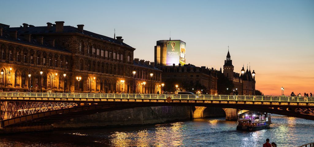 Boat on the river going under a bridge at sunset.