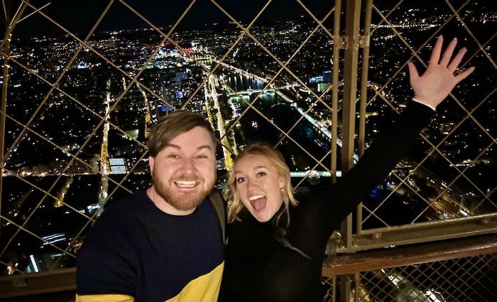 People posing at the top of the Eiffel tower at night