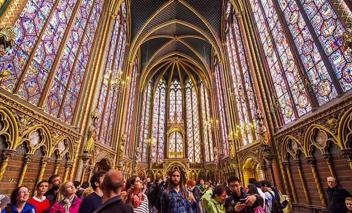 Interior of Sainte-Chapelle with visitors on guided tour in the foreground.