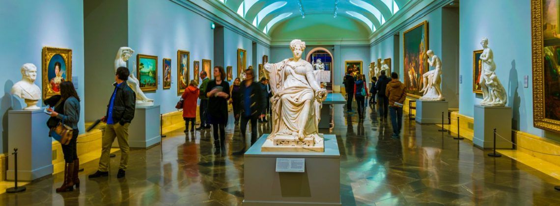 People looking at sculpture in the Prado Museum.