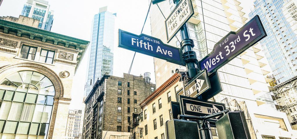 A pole with the street signs of New York.