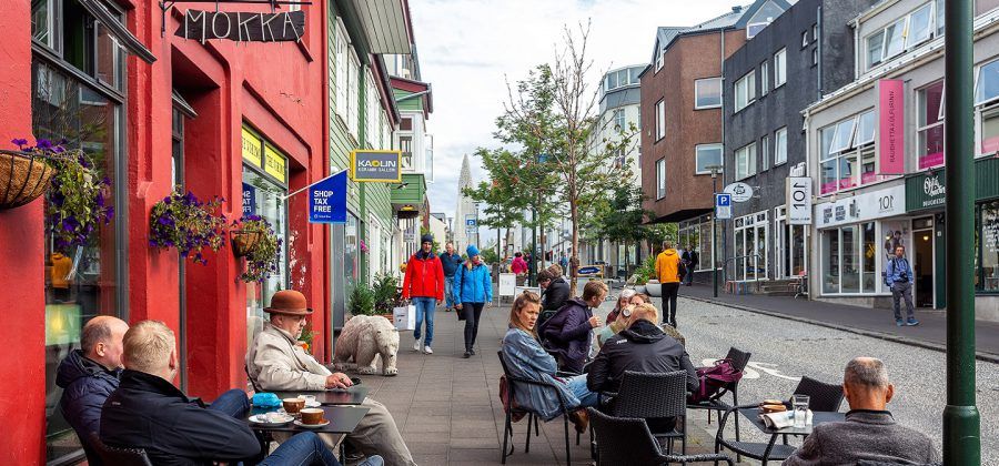 Iceland street with people sitting down drinking coffee. In the background people are walking.