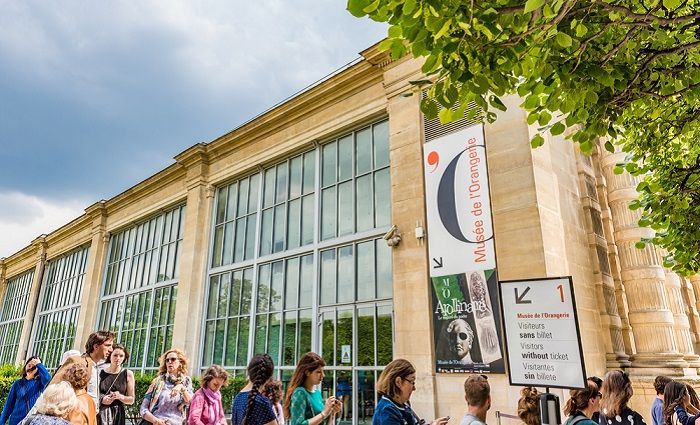 Exterior view of the Musée de l’Orangerie with a long line of visitors waiting to get in.