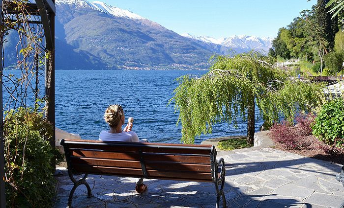 woman on bench eating gelato at lake como