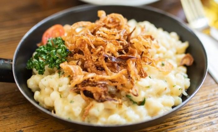 a pot with a serving of Spätzle, a popular local food to try in Vienna of dumplings made with eggs and served with onions and chives