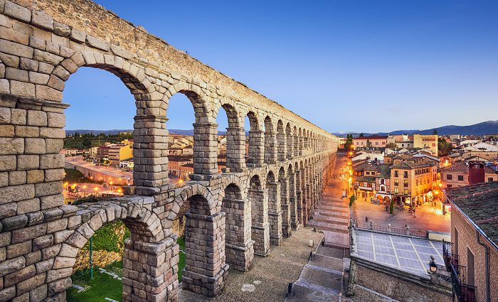 Side view of the Aqueduct of Segovia and the Plaza Azoguejo in the evening.