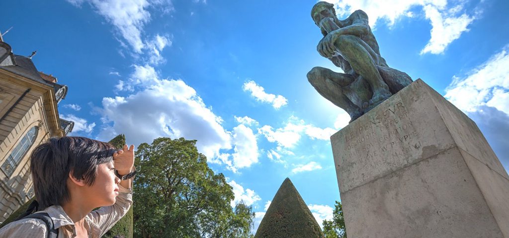 Group at the statue of "The Thinker" by Rodin in the statue garden at Musee Rodin