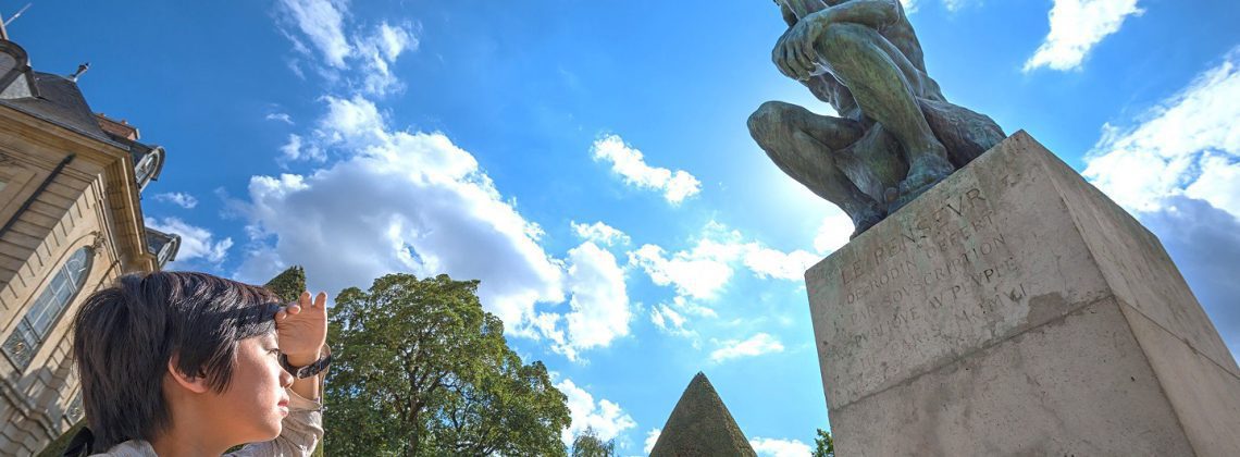 Group at the statue of "The Thinker" by Rodin in the statue garden at Musee Rodin