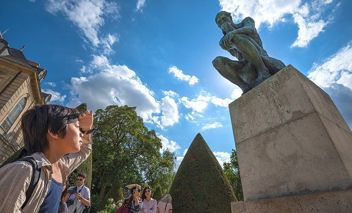 boy looking up at Rodin's sculpture "The Thinker" in the Sculpture Garden of the Rodin Museum in Paris