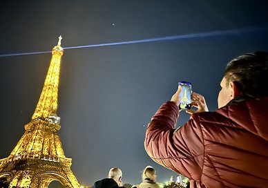 man taking photo of eiffel tower at night
