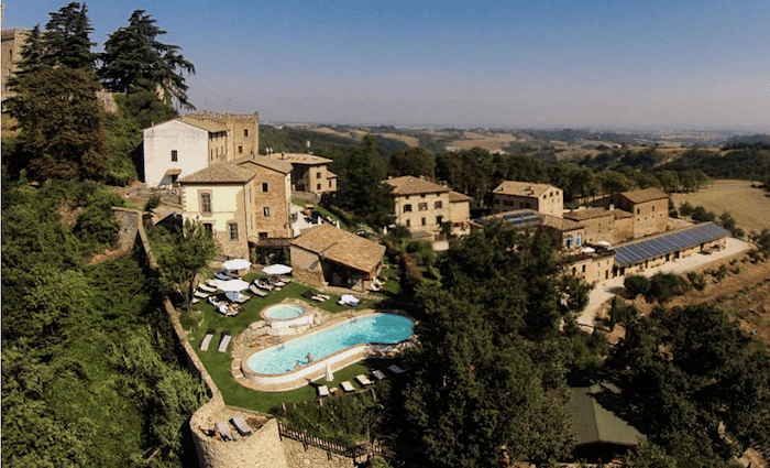 Aerial view over hamlet showing the buildings and pool. With a view over Parma's countryside