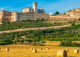 Autumn panorama of Assisi on a sunny day, perched above the surrounding countryside with bales of hay in the fields below
